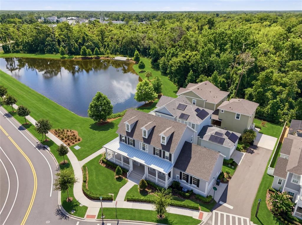 An aerial view shows a two-story house with a wrap-around porch next to a pond — 7565 ESTUARY LAKE LOOP, CELEBRATION, FL