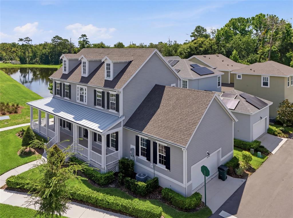 An aerial view of a two-story gray house with a wrap-around porch and pond — 7565 ESTUARY LAKE LOOP, CELEBRATION, FL