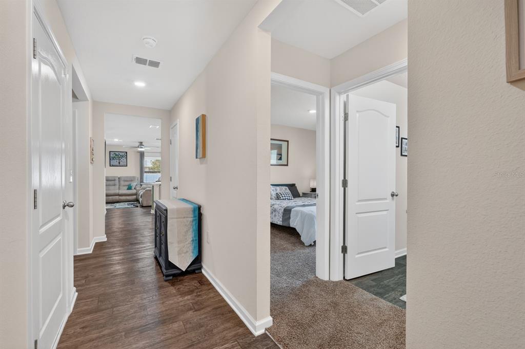 A hallway with wood-look flooring leads to a living area, with a bedroom doorway nearby — 629 GRAND RESERVE DRIVE, BUNNELL, FL