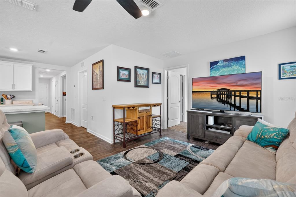 A living room features light-colored sofas, a television on a console, and a wood-topped sideboard — 629 GRAND RESERVE DRIVE, BUNNELL, FL