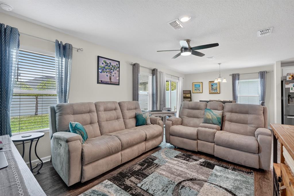 A living room features two beige reclining sofas, a patterned area rug, and window curtains — 629 GRAND RESERVE DRIVE, BUNNELL, FL