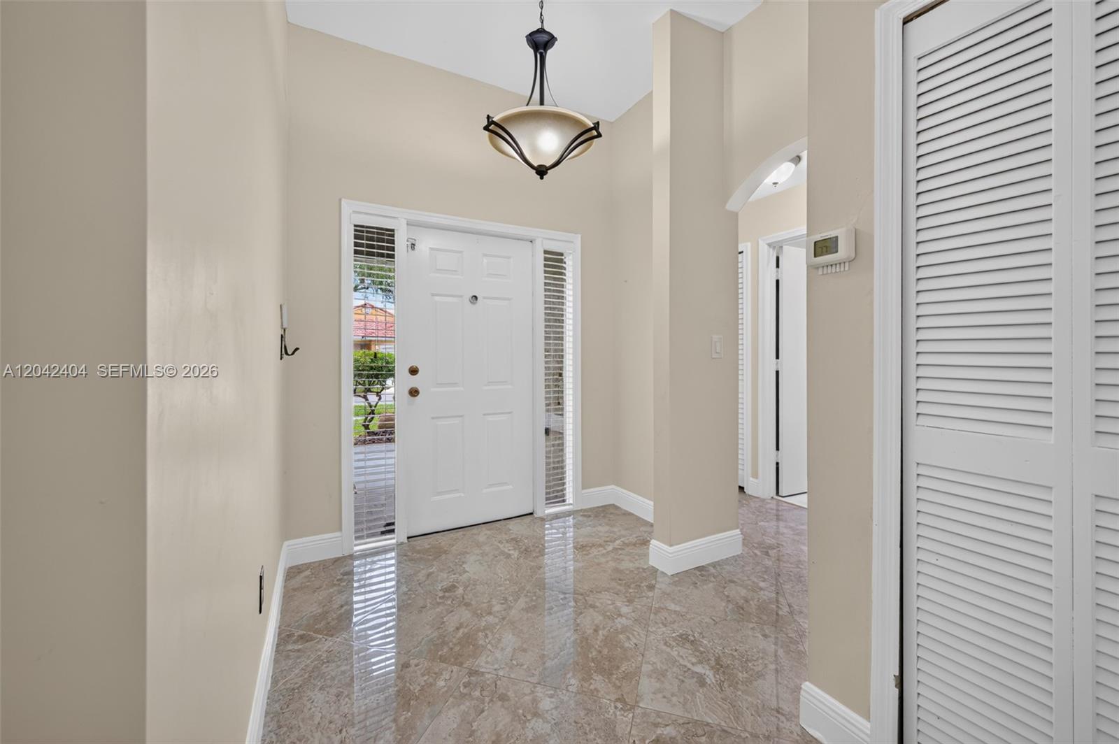 A tiled entryway features a white front door with sidelights and a hanging pendant light — 4950 SW 152nd Ave, Miramar FL 33027, MIRAMAR, FL