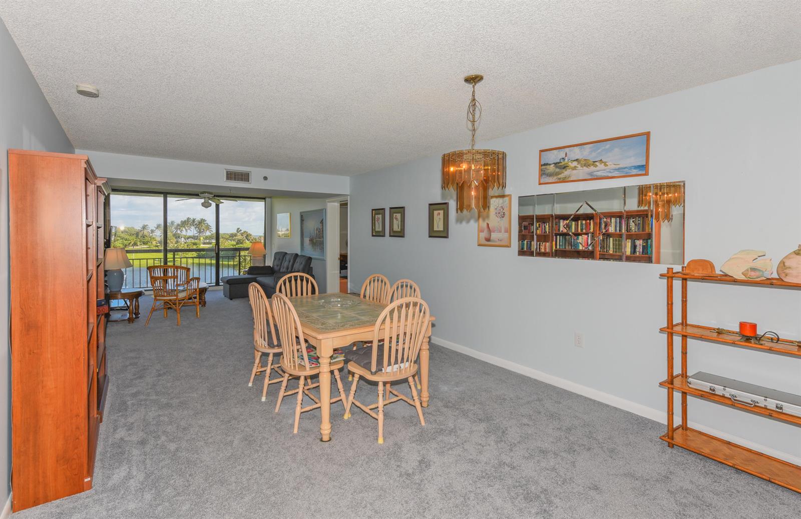 A dining area with a wooden table and chairs sits in a carpeted living space — 601 S Seas Drive # 303, Jupiter FL 33477, JUPITER, FL