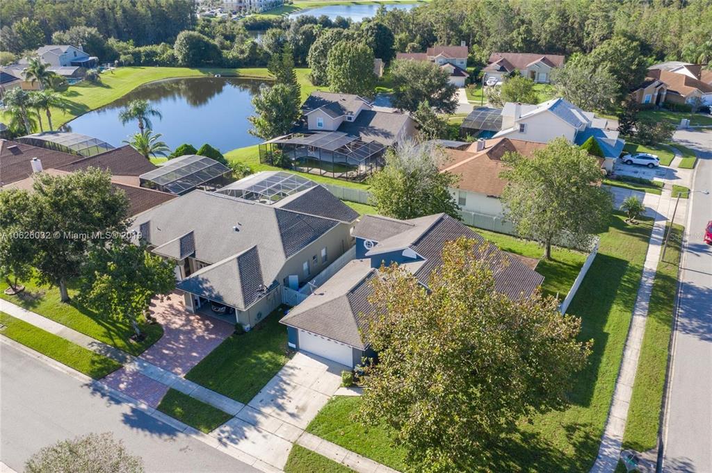 An aerial view shows suburban houses with screened-in pools near a small lake — 14610 ASTINA WAY, ORLANDO, FL