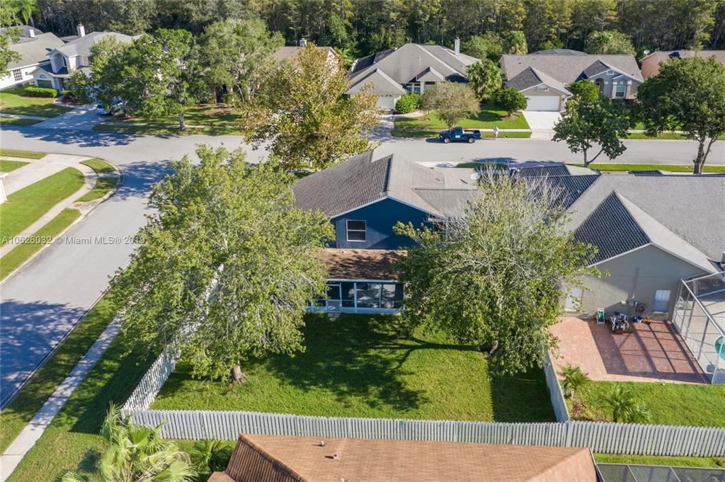 An aerial view shows a blue house with a fenced backyard and two large trees — 14610 ASTINA WAY, ORLANDO, FL