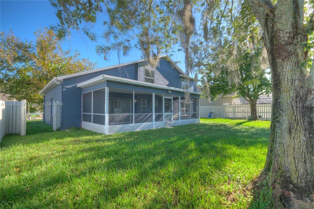 A two-story blue house features a screened-in back porch and a large tree — 14610 ASTINA WAY, ORLANDO, FL