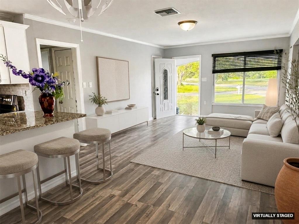 A living room with wood-look flooring, a kitchen island with stools, and a sectional sofa — 309 BELLE CLAIRE PLACE, TEMPLE TERRACE, FL