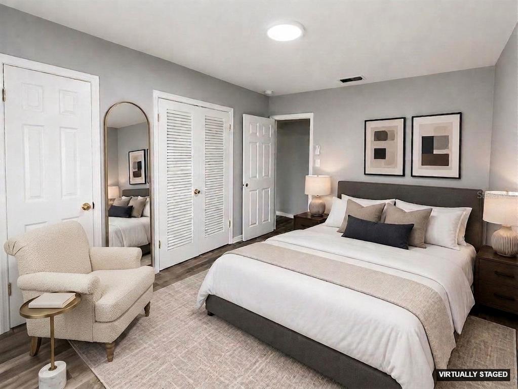 A virtually staged bedroom features a bed, an armchair, a floor mirror, and gray walls — 309 BELLE CLAIRE PLACE, TEMPLE TERRACE, FL