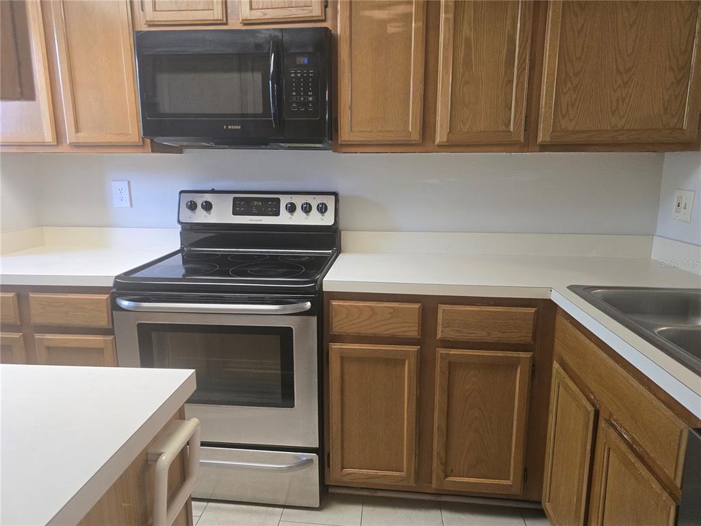 A kitchen features oak cabinets, white countertops, and stainless steel appliances — 8713 LIBERTY PLACE, TAMPA, FL