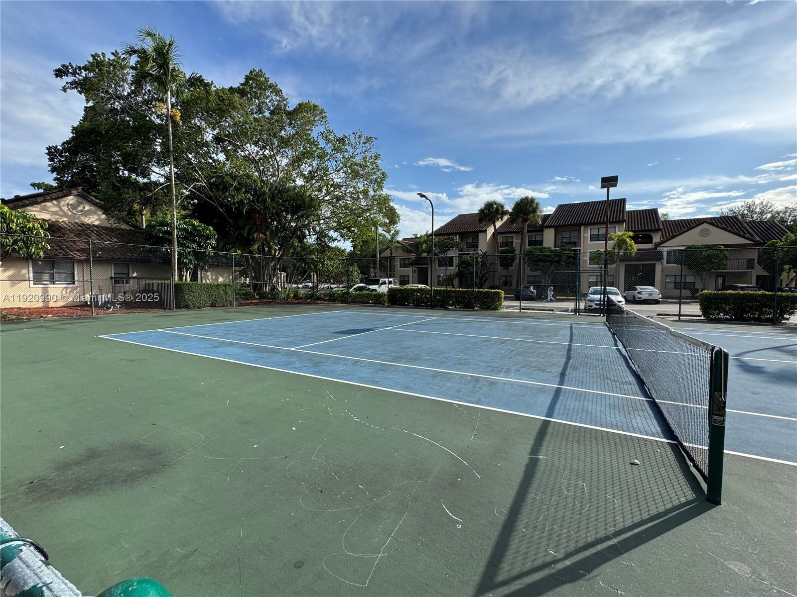 A tennis court with a blue and green surface sits outdoors near apartment buildings — 4341 W Mcnab Rd # 27, Pompano Beach FL 33069, POMPANO BEACH, FL