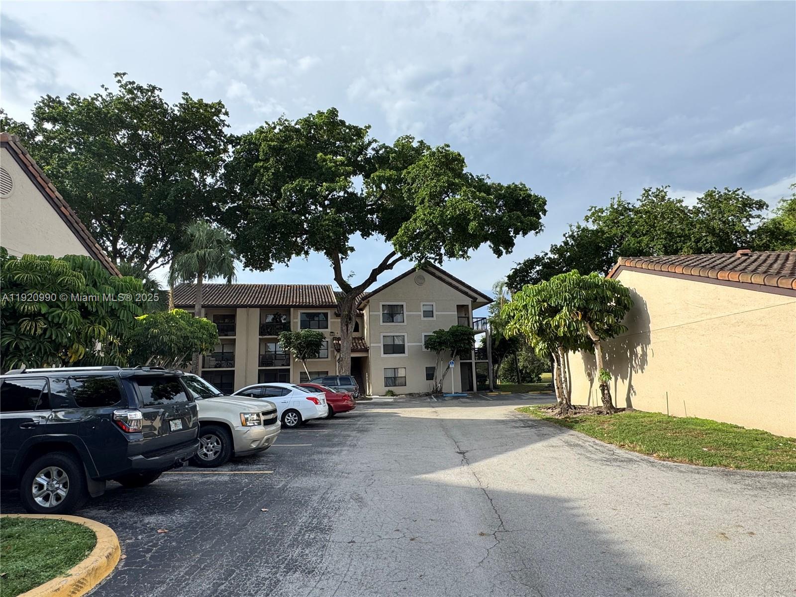 A parking lot sits in front of multi-story apartment buildings surrounded by trees — 4341 W Mcnab Rd # 27, Pompano Beach FL 33069, POMPANO BEACH, FL