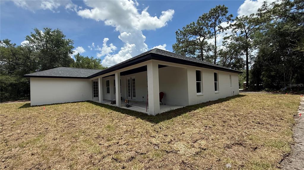 The exterior of a white house features a covered patio and a large grassy yard — 35031 PRIMROSE LANE, WEBSTER, FL