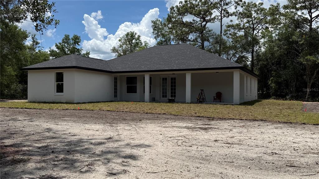The exterior of a white, single-story house with a dark roof and a covered patio — 35031 PRIMROSE LANE, WEBSTER, FL