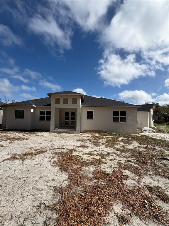 A single-story house with a beige stucco exterior and a dark shingled roof — 589 CHRISTINA LAKE DRIVE, LAKELAND, FL
