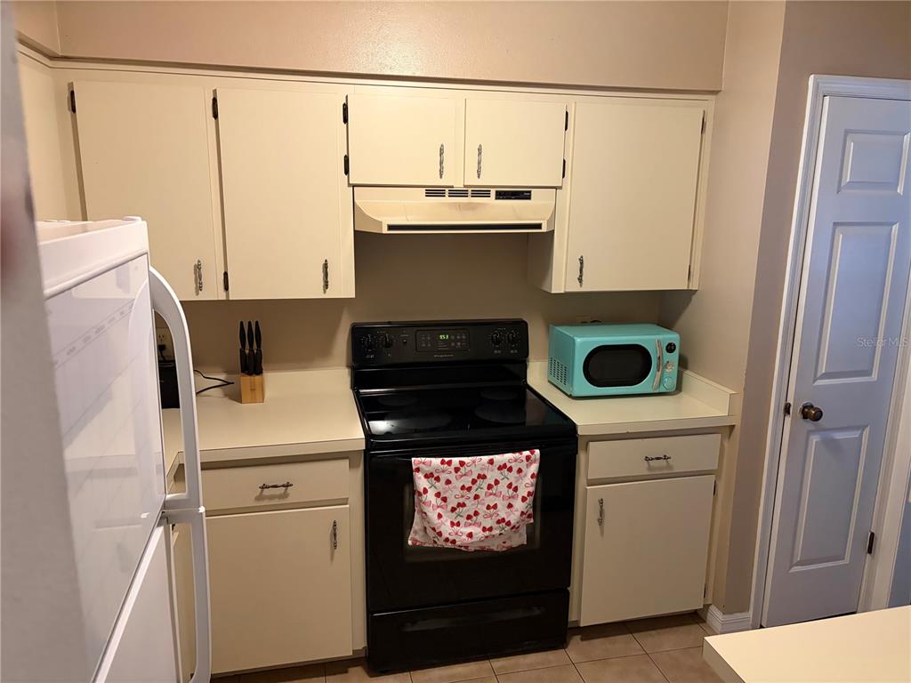 A kitchen features off-white cabinets, a black electric range, and a light blue microwave — 821 SLEEPY HARBOUR DRIVE, OCOEE, FL