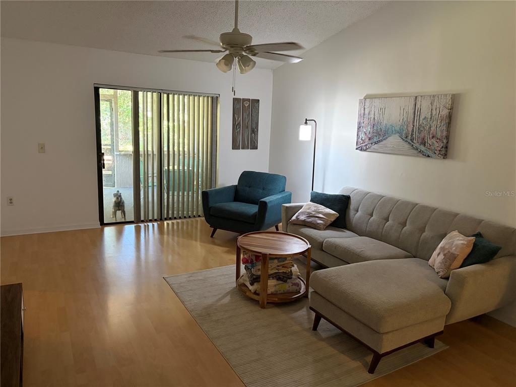 A living room features light wood flooring, a gray sectional sofa, and a blue armchair — 821 SLEEPY HARBOUR DRIVE, OCOEE, FL