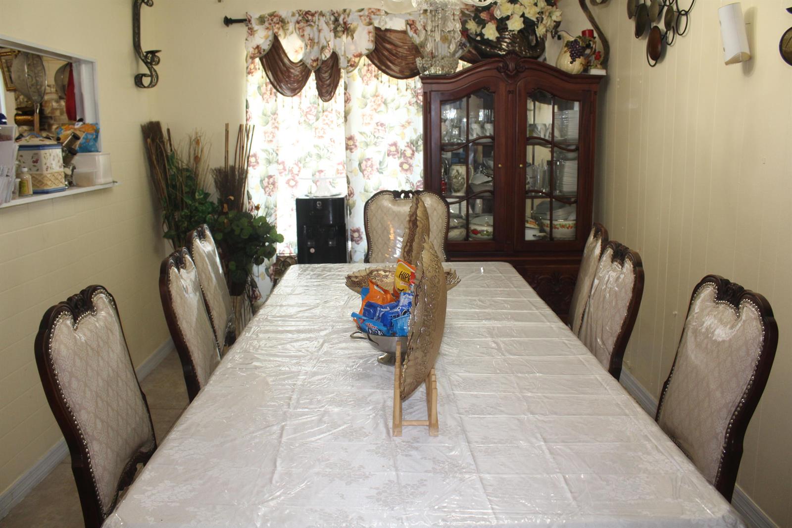 A dining room features a long table with chairs, a china cabinet, and floral curtains — 431 S Chillingworth Drive, West Palm Beach FL 33409, WEST PALM BEACH, FL