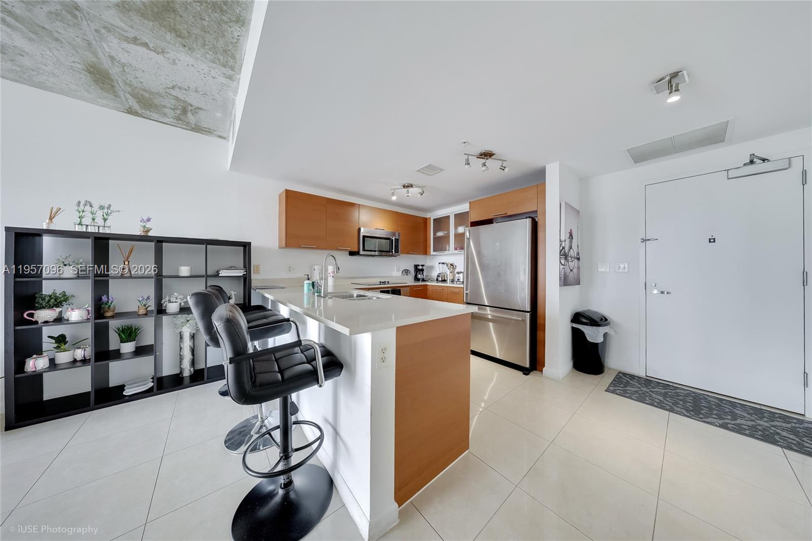 A modern kitchen features wood cabinets, stainless steel appliances, and a breakfast bar with stools — 3250 NE 1st Ave # 811, Miami FL 33137, MIAMI, FL
