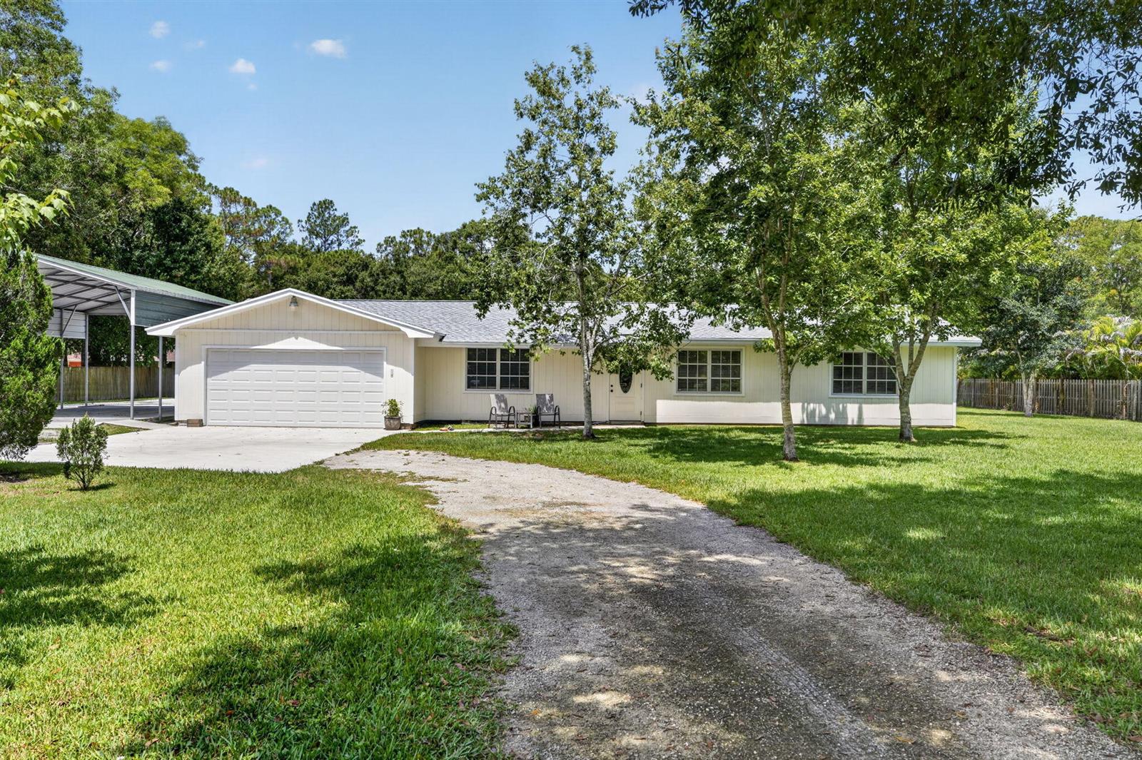 A single-story house with a white exterior, attached garage, and a gravel driveway — 17751 127th Drive N, Jupiter FL 33478, JUPITER, FL