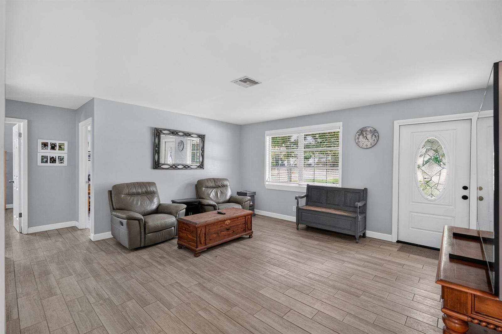 A living room features light gray walls, wood-look tile flooring, two recliners, and a wooden chest — 17751 127th Drive N, Jupiter FL 33478, JUPITER, FL