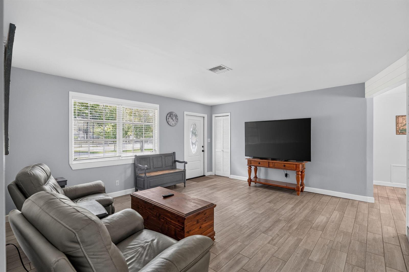 A living room features gray walls, wood-look tile flooring, a television, and a gray bench — 17751 127th Drive N, Jupiter FL 33478, JUPITER, FL