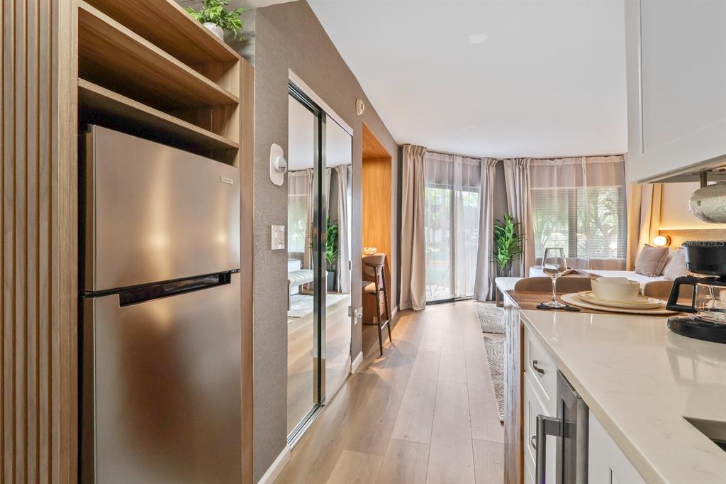 A kitchen area with stainless steel appliances overlooks a bedroom with a sliding glass door — 6165 CARRIER DRIVE UNIT 2108, ORLANDO, FL