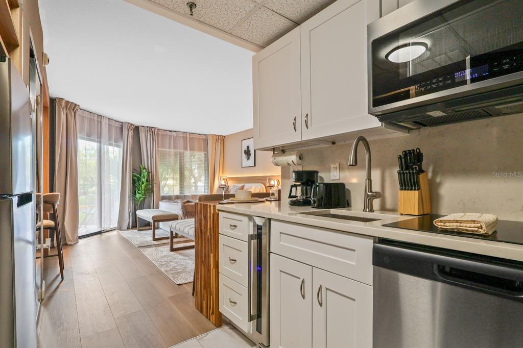A kitchen with white cabinets and stainless steel appliances opens into a living area — 6165 CARRIER DRIVE UNIT 2108, ORLANDO, FL