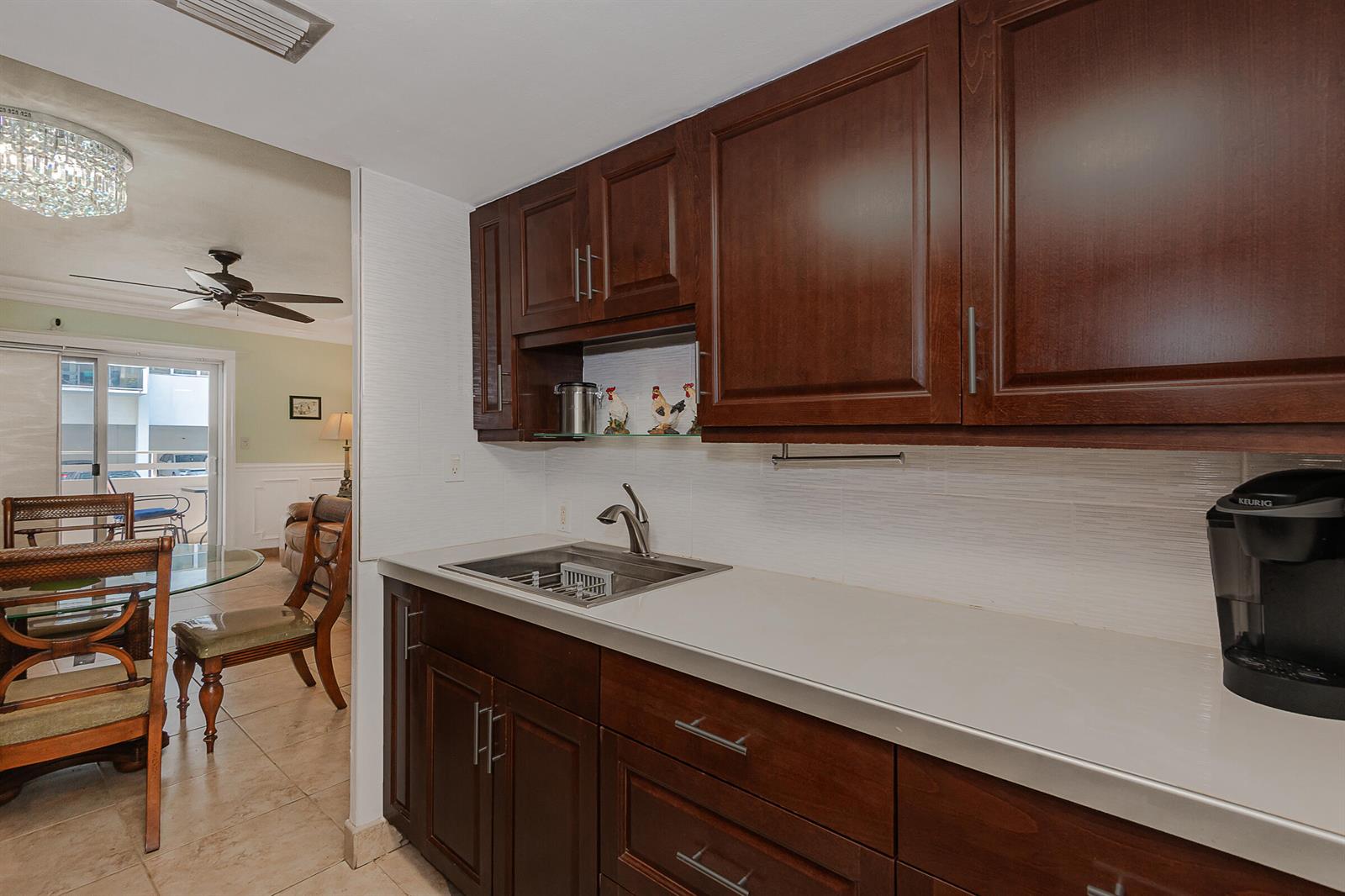 A kitchen features dark wood cabinets, a stainless steel sink, and white tiled backsplash — 2076 S Ocean Drive # 207, Hallandale Beach FL 33009, HALLANDALE BEACH, FL
