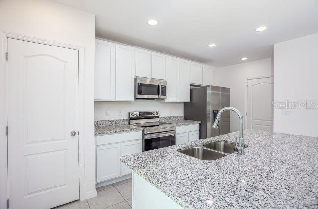 A kitchen features white cabinets, granite countertops, stainless steel appliances, and a central island — 8099 SW 9TH LANE, GAINESVILLE, FL