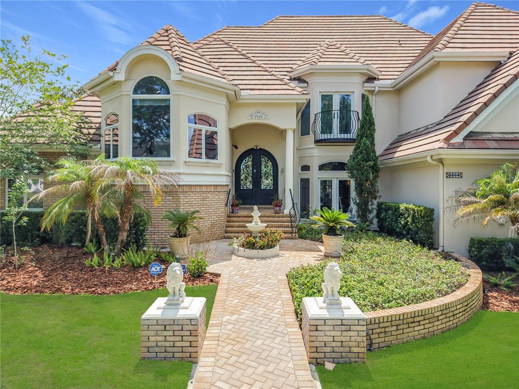 A two-story house with a brick walkway, lion statues, and a tiled roof — 2204 CAIRNS COURT, ORLANDO, FL