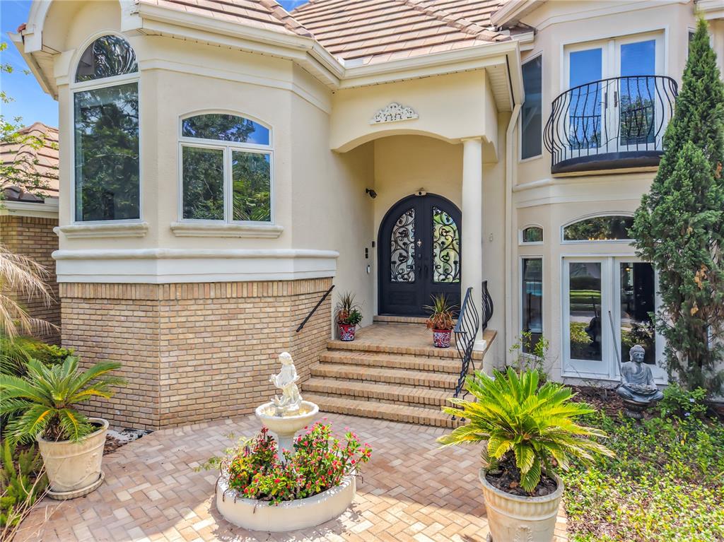 The exterior of a two-story house features a brick base, arched double doors, and landscaping — 2204 CAIRNS COURT, ORLANDO, FL