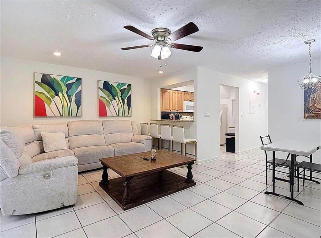 A living room with tile floors, a sectional sofa, a coffee table, and a breakfast bar — 10131 LAKE OAK CIRCLE, TAMPA, FL