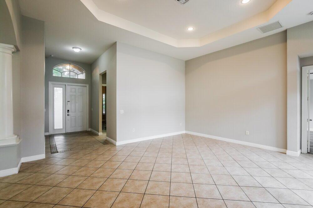 An empty room with beige tile flooring, light gray walls, and a tray ceiling — MIRAMAR, FL