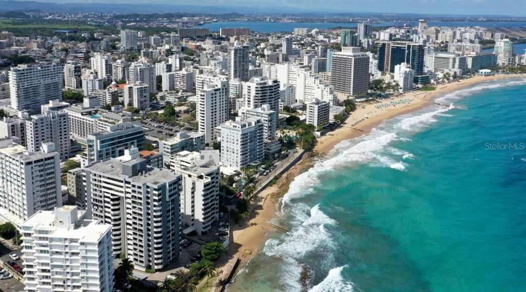 An aerial view of a coastal city with high-rise buildings lining a sandy beach — 2 WASHINGTON STREET UNIT 1201, SAN JUAN, PR