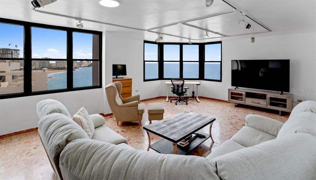 A living room with a sectional sofa, a desk, and large windows overlooking the ocean — 2 WASHINGTON STREET UNIT 1201, SAN JUAN, PR