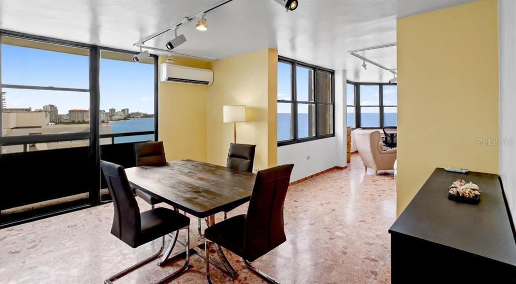 A dining area with a wooden table, dark chairs, and large windows overlooking the ocean — 2 WASHINGTON STREET UNIT 1201, SAN JUAN, PR
