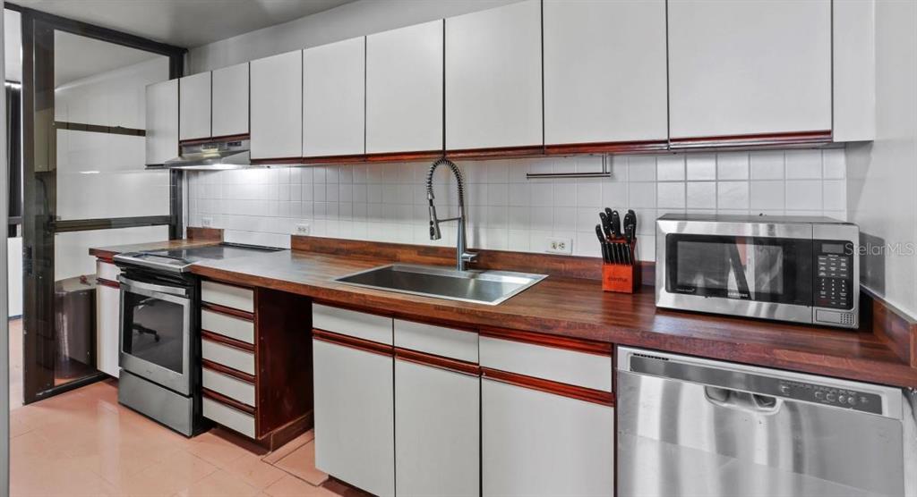 A kitchen features white flat-panel cabinets, a wood countertop, and stainless steel appliances — 2 WASHINGTON STREET UNIT 1201, SAN JUAN, PR