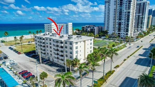 An aerial view shows a multi-story apartment building near a beach with a red arrow — 1901 S Ocean Drive # 202, Hollywood FL 33019, HOLLYWOOD, FL