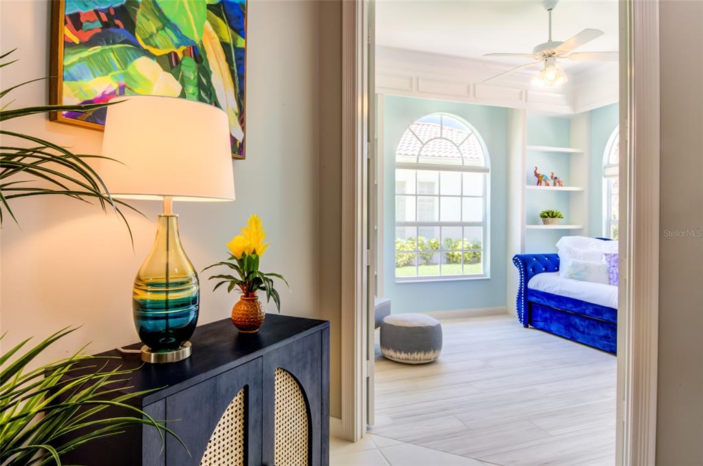A view through a doorway into a bright room with a blue daybed and arched windows — 5622 OCTONIA PLACE, SARASOTA, FL