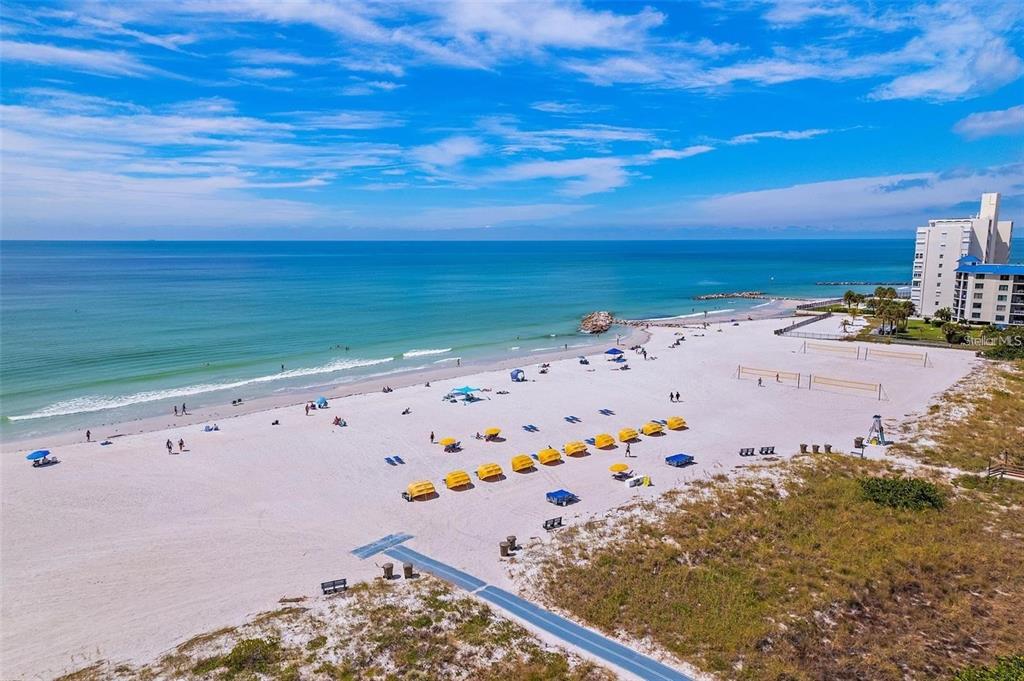 A balcony with a wicker chair, small table, and view of a street and ocean — 7003 SUNSET WAY UNIT 8, ST PETE BEACH, FL