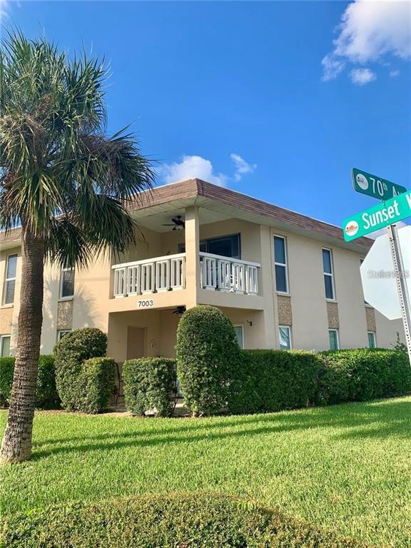 An aerial view shows a coastal neighborhood with a red arrow pointing to a building — 7003 SUNSET WAY UNIT 8, ST PETE BEACH, FL