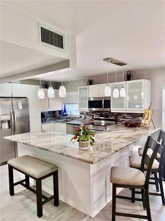 An open-concept kitchen with granite countertops and pendant lighting overlooks a living room area — 7003 SUNSET WAY UNIT 8, ST PETE BEACH, FL