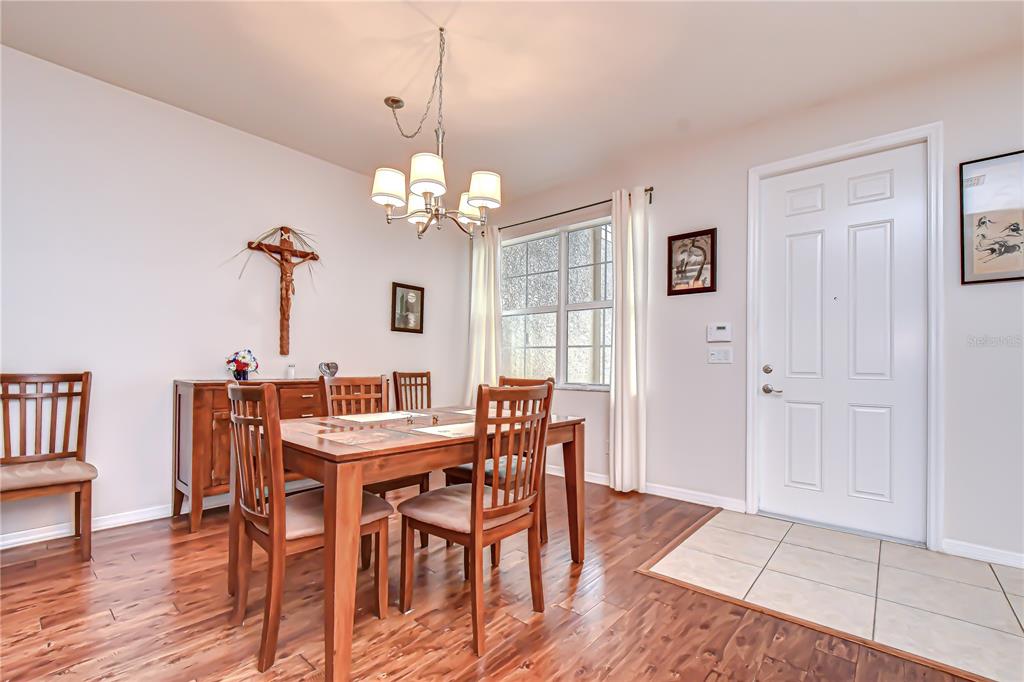 A dining room with a wooden table, chairs, a chandelier, and a white front door — 16158 AMETHYST KEY DRIVE, WIMAUMA, FL