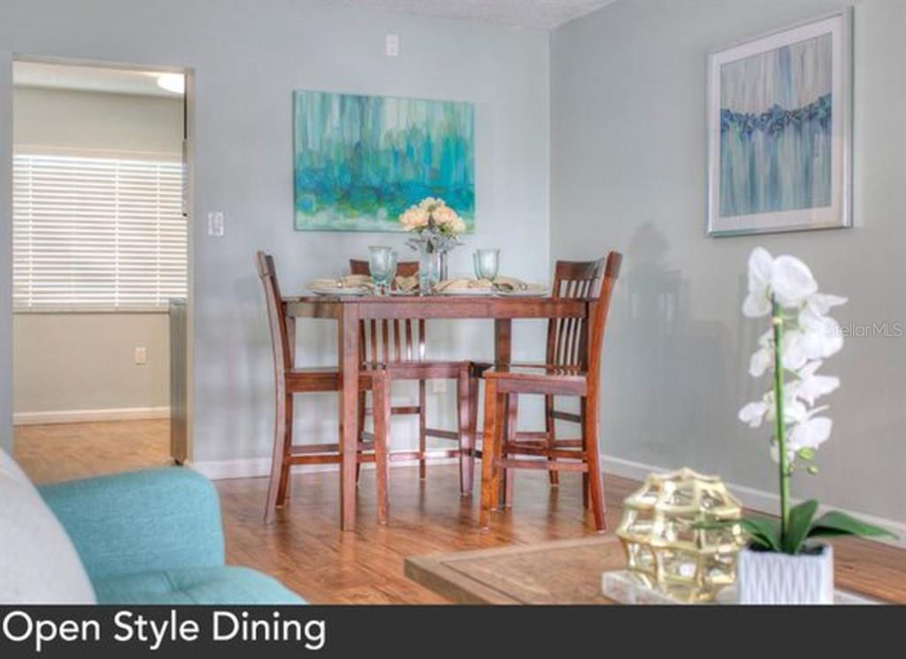 A dining area features a wooden table with four chairs, wall art, and hardwood flooring — 1824 SHORE DRIVE S UNIT 201, SOUTH PASADENA, FL