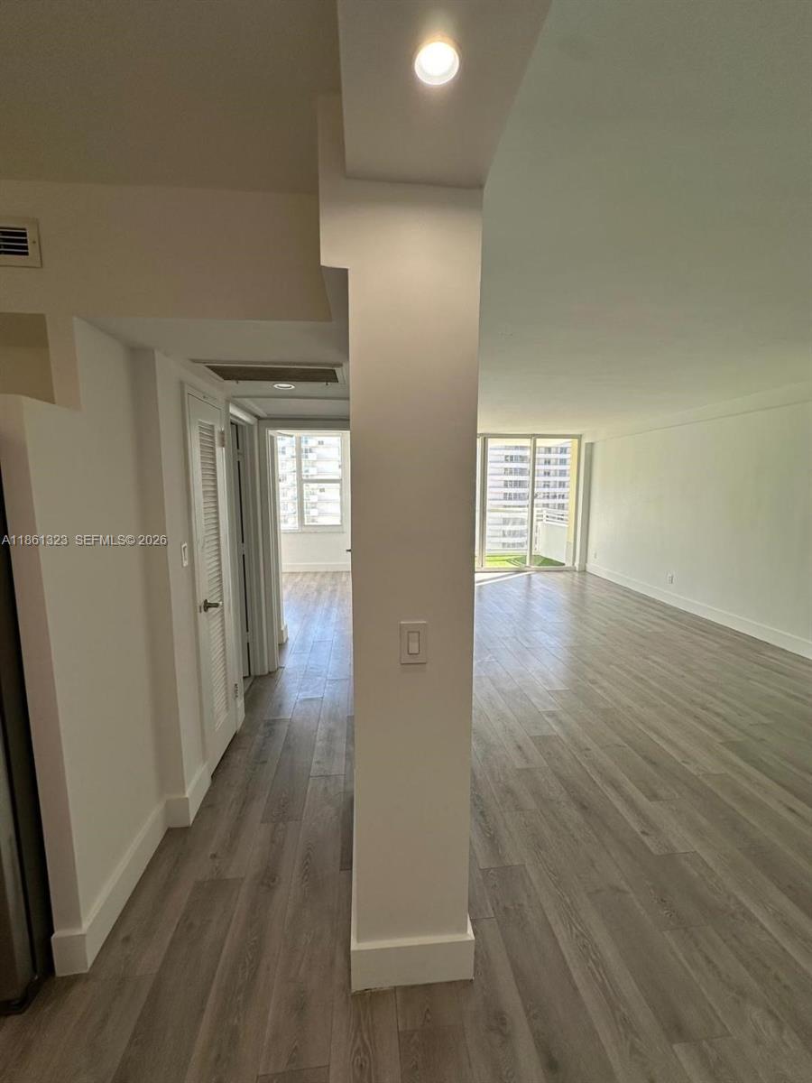 An interior view shows a living area with light wood-look flooring and a central pillar — 5600 Collins Ave # 11W, Miami Beach FL 33140, MIAMI BEACH, FL