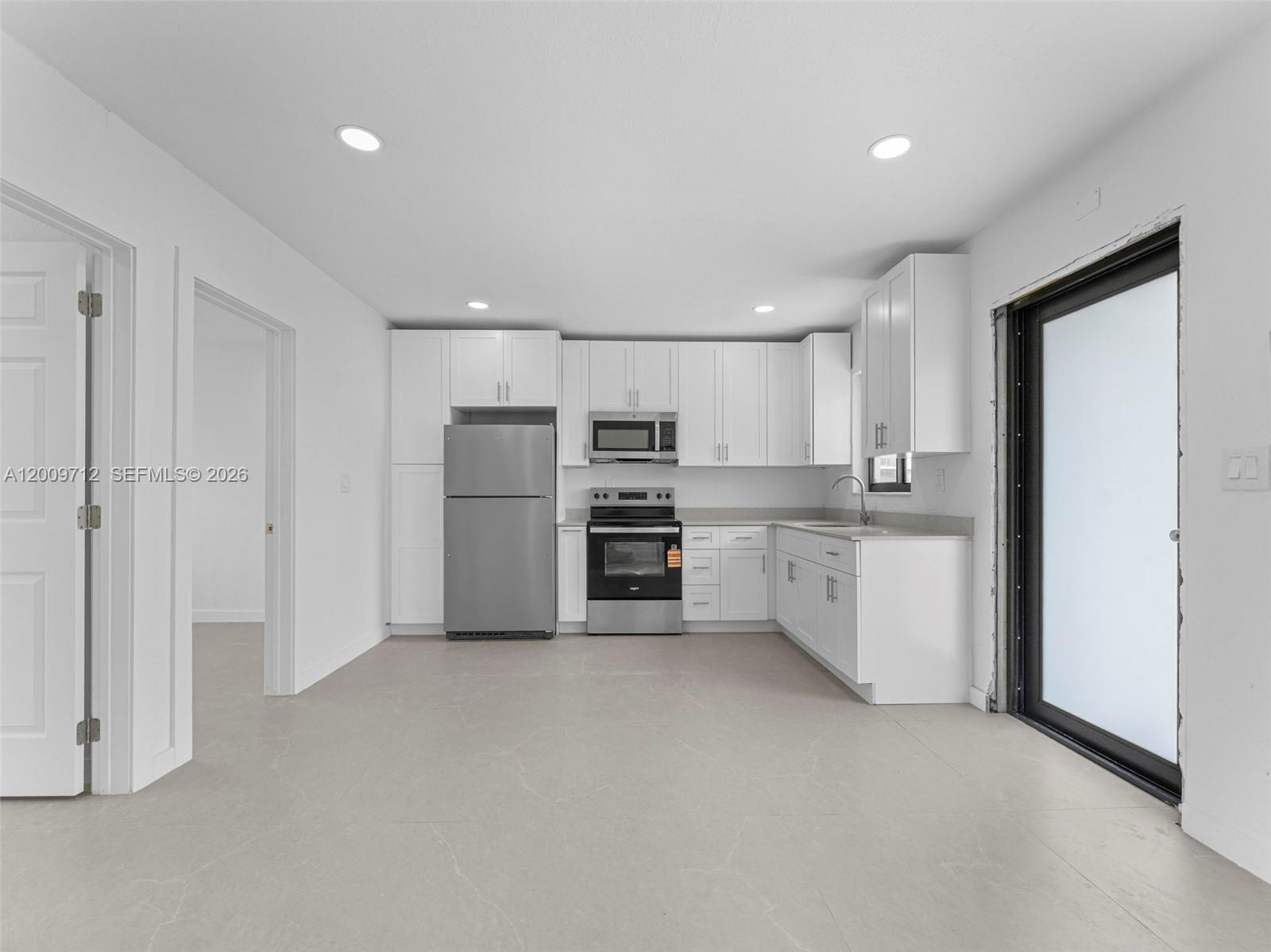 A kitchen features white cabinets, stainless steel appliances, and light gray tile flooring — 1368 W 29th St # 2, Hialeah FL 33012, HIALEAH, FL