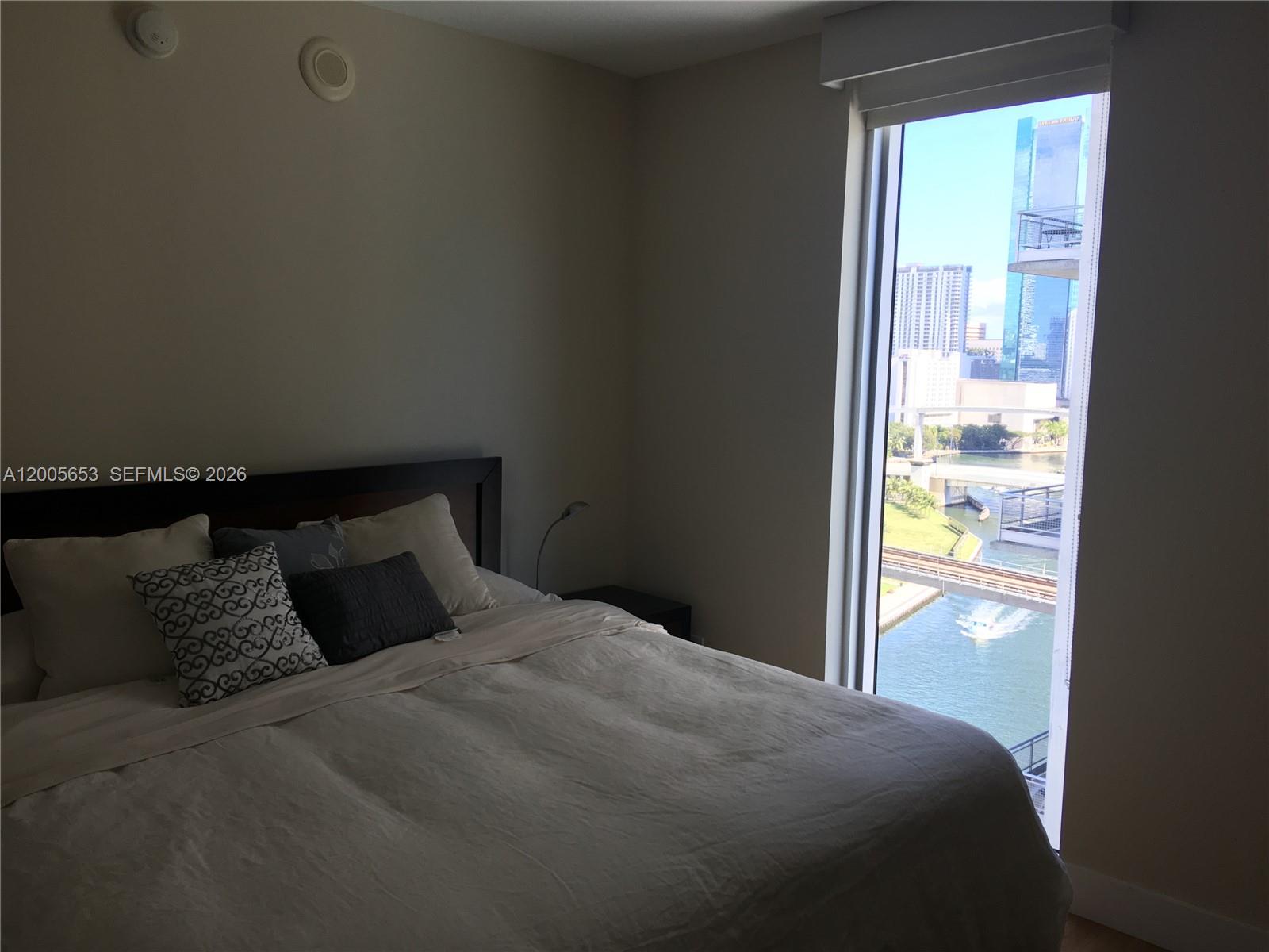 A bedroom with a large bed and a window overlooking a city waterway — 185 SW 7th St # 1511, Miami FL 33130, MIAMI, FL