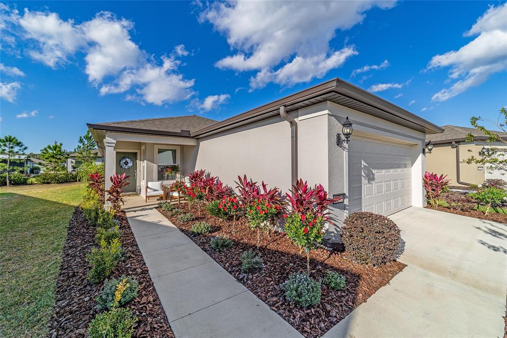 A single-story house exterior features a concrete walkway, a garage, and a landscaped front yard — 5472 SW 85TH AVENUE ROAD, OCALA, FL