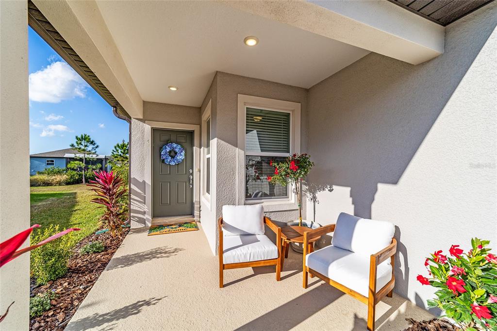 A covered front porch features two wooden chairs, a small table, and a front door — 5472 SW 85TH AVENUE ROAD, OCALA, FL