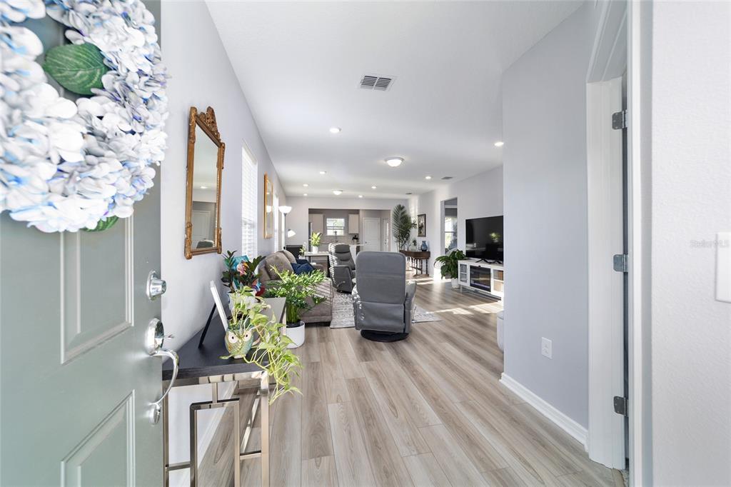 An entryway leads into an open-concept living area with light wood-look flooring and gray walls — 5472 SW 85TH AVENUE ROAD, OCALA, FL